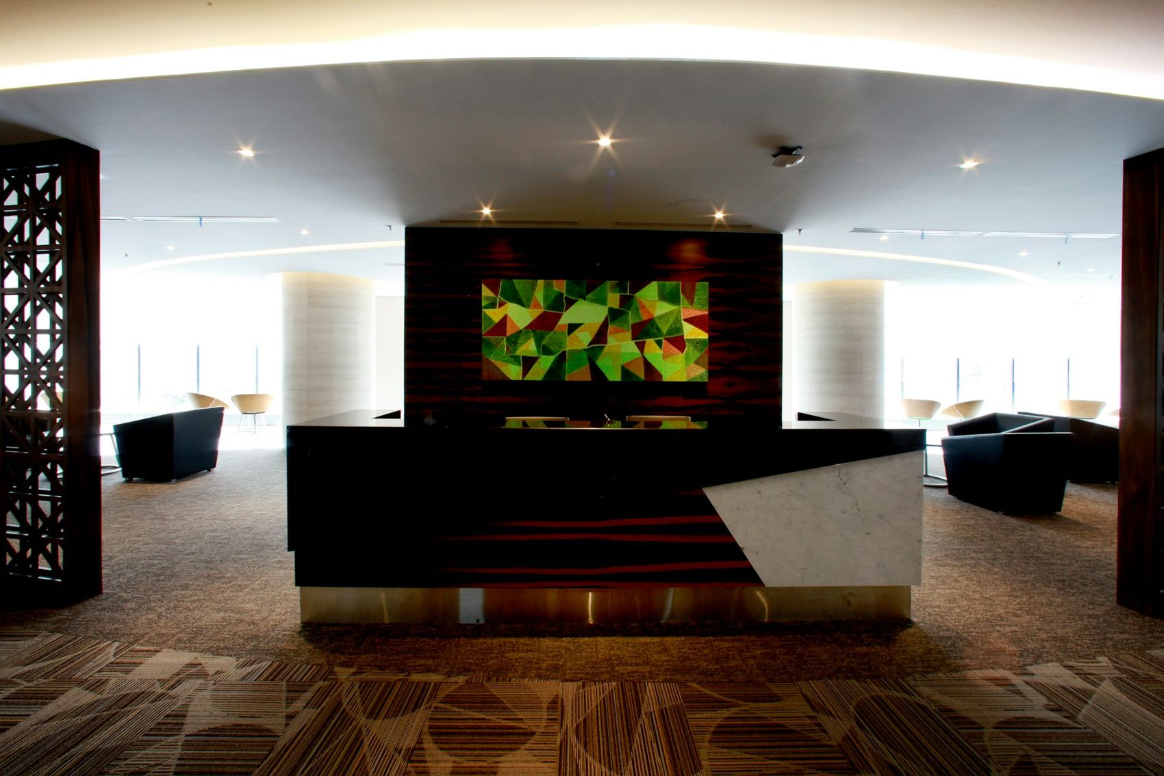 Modern clinic reception with a marble-and-wood desk, abstract wall art, and waiting chairs beyond