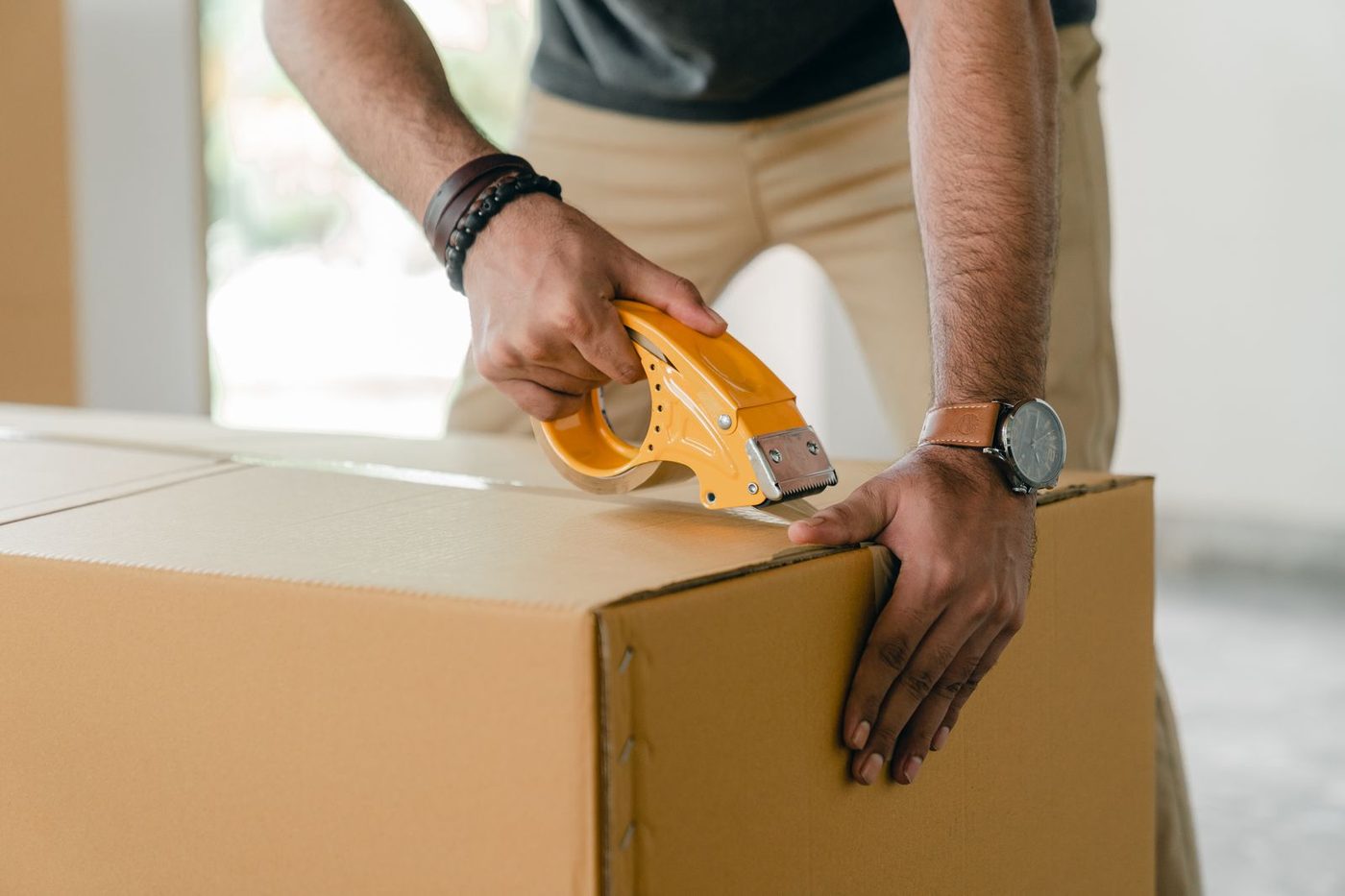 Hands sealing a packing carton with tape in the atelier — print-on-demand fulfillment