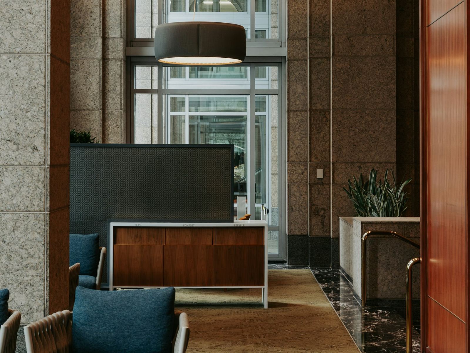High-ceiling stone lobby with blue lounge chairs and a marble floor, no competing wordmark