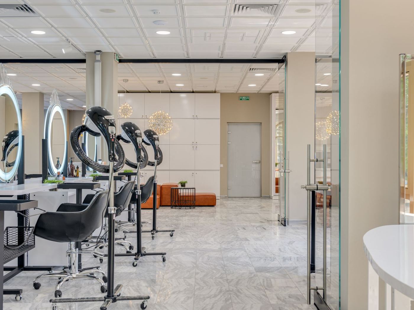 Commercial salon floor with marble tiles, LED ring mirrors, and a cognac bench, no third-party wordmark