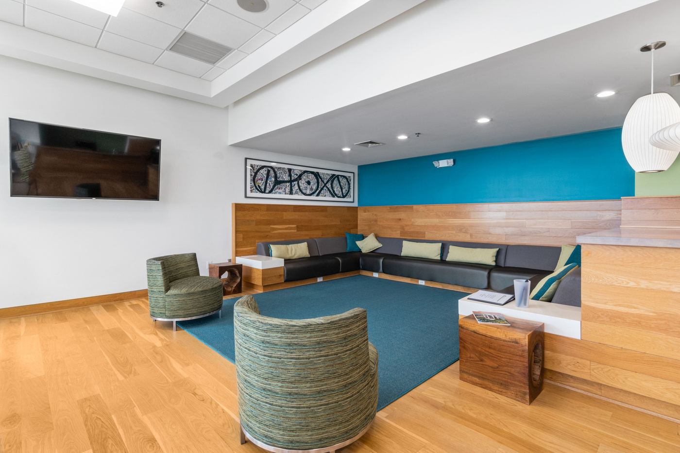 Commercial clinic waiting lounge with built-in benches, moss-green chairs, and a wood reception counter